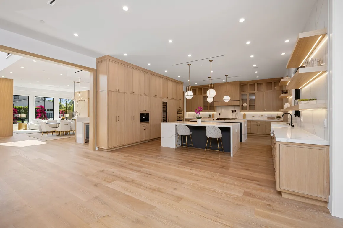 Open-concept kitchen and hall with white cabinets, center island, and wood flooring