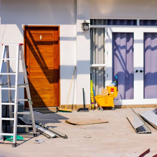 Front entrance of a house under renovation with tools and materials scattered around.